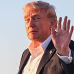 President Donald Trump waves to the press.