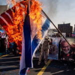 People burn the American and Israel flag in the streets of Iran.