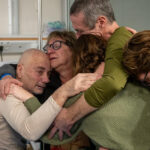 Five people hug each other in a hospital.