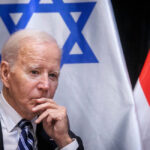 President Joe Biden sitting in front of The Israeli and American flags