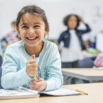 Young Girl in Class at Her Desk Laughing