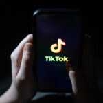 Children's hands hold a phone with the TikTok logo displayed.