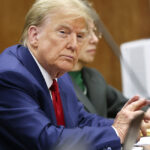 President Donald Trump sitting at a table in court with one of its attorneys