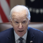 President Joe Biden sitting at a desk with a U.S. flag behind him