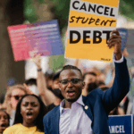 Several black students outdoors holding up signs saying cancel student debt