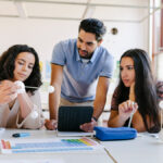 Three high school science students look at models in class.