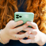 A young woman holding a cell phone with both hands.
