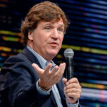 Tucker Carlson speaking through a microphone.