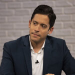 Michael Knowles in a black sport coat and a white shirt stares intently
