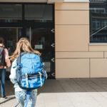 Kids run into school with backpacks