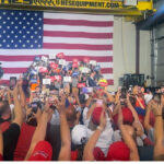 Sen. JD Vance speaks at a factory with a large American flag as his backdrop.