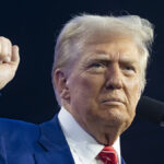 Donald Trump raises his fist in a blue suit
