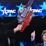 Elon Musk (L) holds a chainsaw high that Argentine President Javier Milei (R) gave him to represent how he’s cutting government.