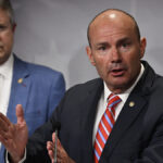 Mike Lee in a black suit with a striped tie