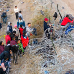 Illegal aliens try to pass over razor wire after crossing the border into El Paso, Texas.