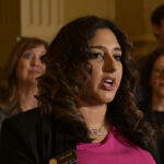 Yara Zokaie wearing a name tag and a pink blouse with a few female Democrats behind her