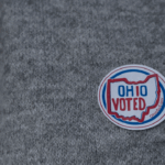 A round sticker reading OHIO VOTED with an outline of Ohio is on a gray sweater.
