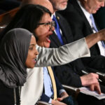 Reps. Ilhan Omar and Rashida Tlaib sit in the House chamber, both shouting, Tlaib pointing. People are seated beside and behind them.