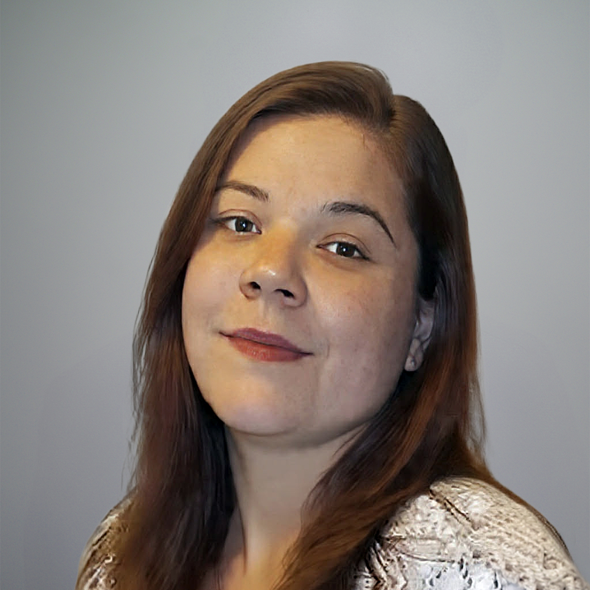 A woman with straight brown hair and light skin, wearing a patterned white top, smiles softly at the camera against a plain gray background.