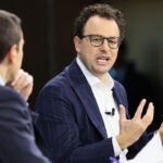 Dario Amodei and another man sit and talk during an interview or panel discussion.