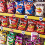 Shelves stocked with assorted bags of Mexican chips, including Ruffles, Sabritas, and Doritos, in various colorful packaging, with some Pringles cans at the bottom.