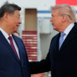 Xi Jinping and Donald Trump in suits stand outdoors, talking to each other. Xi faces forward, smiling, while Trump gestures with his hand. An airplane with a staircase is visible in the background.