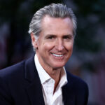 California Gov. Gavin Newsom wearing a dark suit and white button-down shirt.