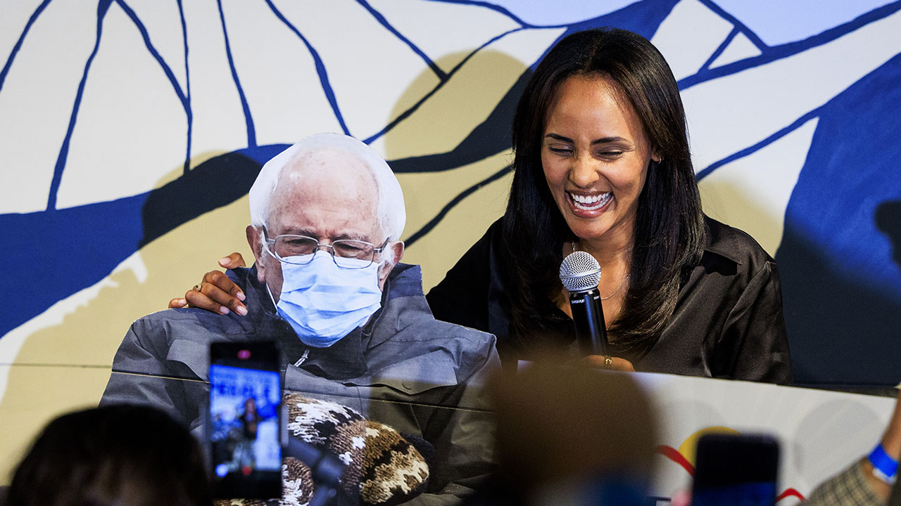 Melat Kiros, a DSA candidate, smiles with a cardboard cutout of Bernie Sanders wearing a mask.