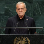 Iran's president stands at a podium with a United Nations emblem, speaking into microphones.