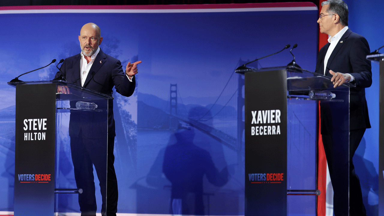 Steve Hilton and Xavier Becerra stand at individual podiums labeled Voters Decide during a televised debate on affordability.