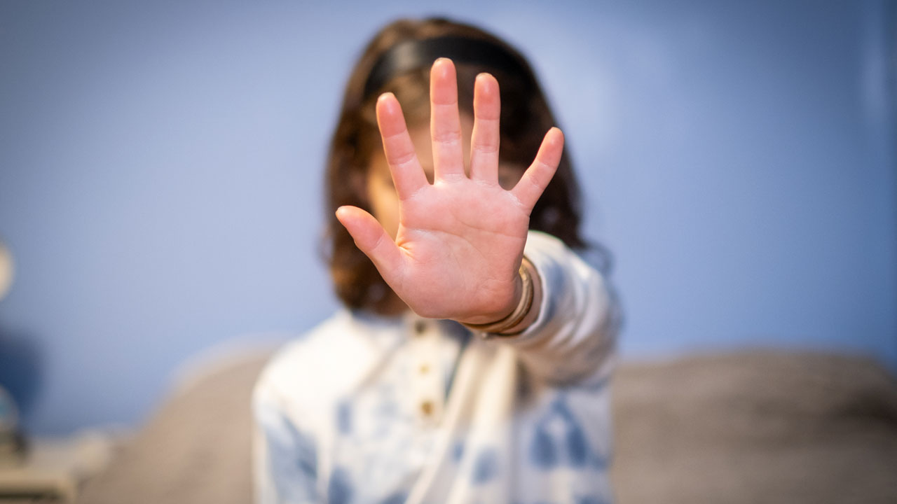 A person holds their open hand up toward the camera in a gesture to stop a scandal.
