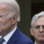President Joe Biden speaks while Attorney General Merrick Garland stands behind him.