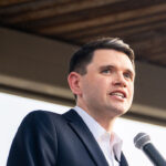 James Talarico in a dark suit speaks into a microphone.