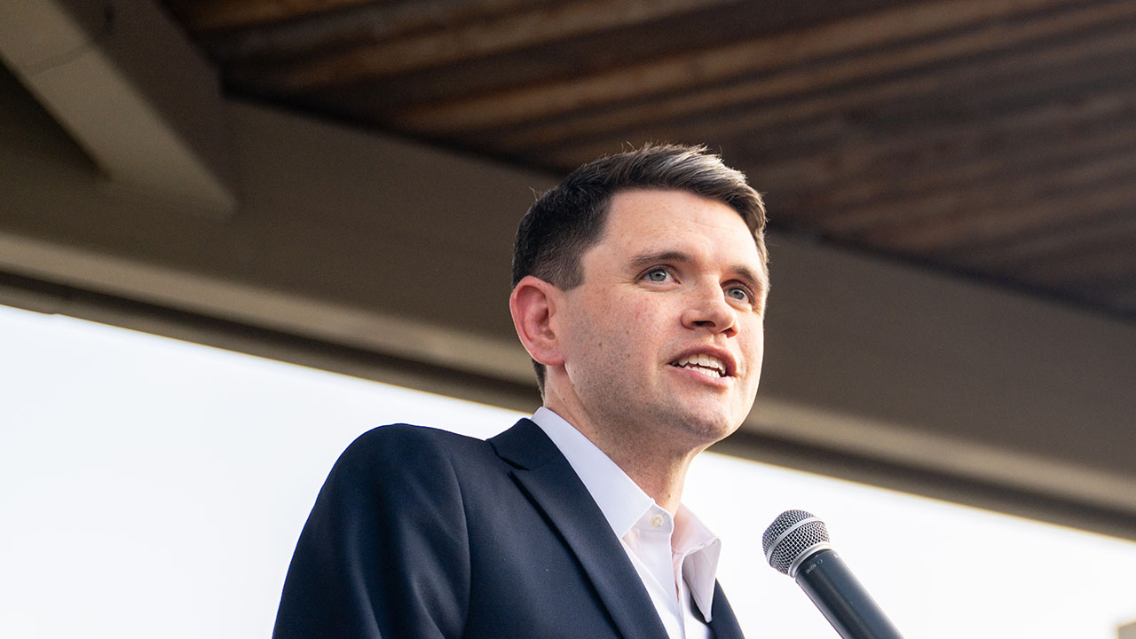 James Talarico in a dark suit speaks into a microphone.
