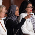 Representative Ilhan Omar gestures and speaks while seated alongside Representatives Rashida Tlaib and others during a session of Congress.