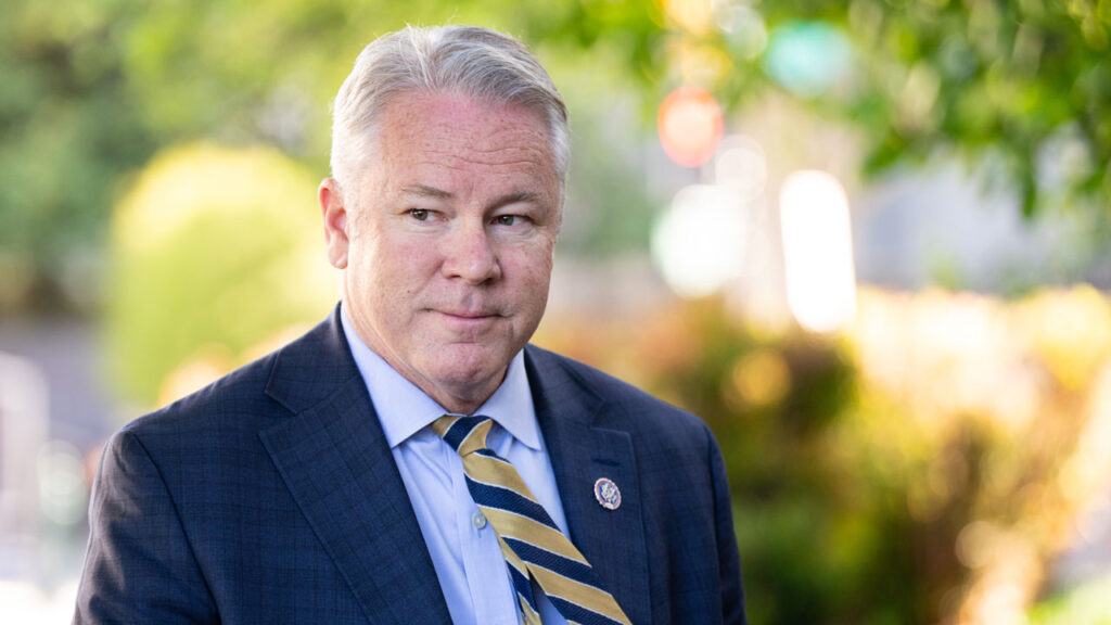 Middle-aged man in a suit and tie with a congressional lapel pin.