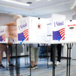 People at voting booths with I Voted signs in a polling station.