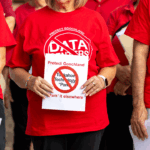 Three people wearing red shirts with a Protect Goochland: No Data Centers logo, with the center person holding a sign that says Protect Goochland: Tuckahoe Technology Park it elsewhere.