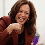 Kamala Harris laughs while holding a microphone with a sparkly purple cover.