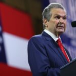 Rick Jackson is pictured and speaks at a podium in front of a Georgia state flag.