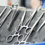 Do No Harm is demanding medical associations unequivocally condemn transgender genital surgeries for minors. Pictured: Several metal surgical instruments, including scissors and forceps, are neatly arranged on a sterile tray covered with a blue drape, ready for use in a medical procedure.