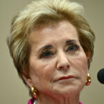 Department of Education staff recommended against renewing the ABA's ability to accredit law schools. Pictured: Linda McMahon, a woman with short blond hair, wearing gold earrings and a pink top, looks serious while sitting in front of a microphone during a formal event.