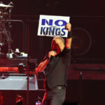 Bruce Springsteen, in concert, holding up a "No Kings" sign.