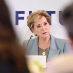 Secretary of Education Linda McMahon sits on a panel, viewed from between the heads of two women.