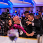 White House Deputy Chief of Staff Steven Miller protects his wife as agents try to usher him out of White House Correspondents' Dinner.