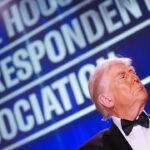 President Trump in profile in bottom right of shot underneath large "White House Correspondents' Dinner" sign.