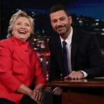 Hillary Clinton, in a red pantsuit, poses with Jimmy Kimmel on the set of his ABC late night show.