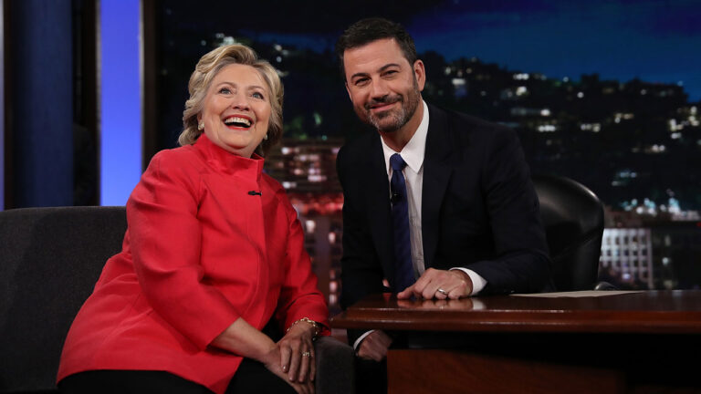 Hillary Clinton, in a red pantsuit, poses with Jimmy Kimmel on the set of his ABC late night show.