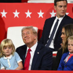 Donald Trump with granddaughter in his lap, grandson at his side, daughter and son-in-law behind him, and JD Vance to his right.