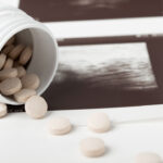 Pills spill out of a white bottle onto the edge of an ultrasound.